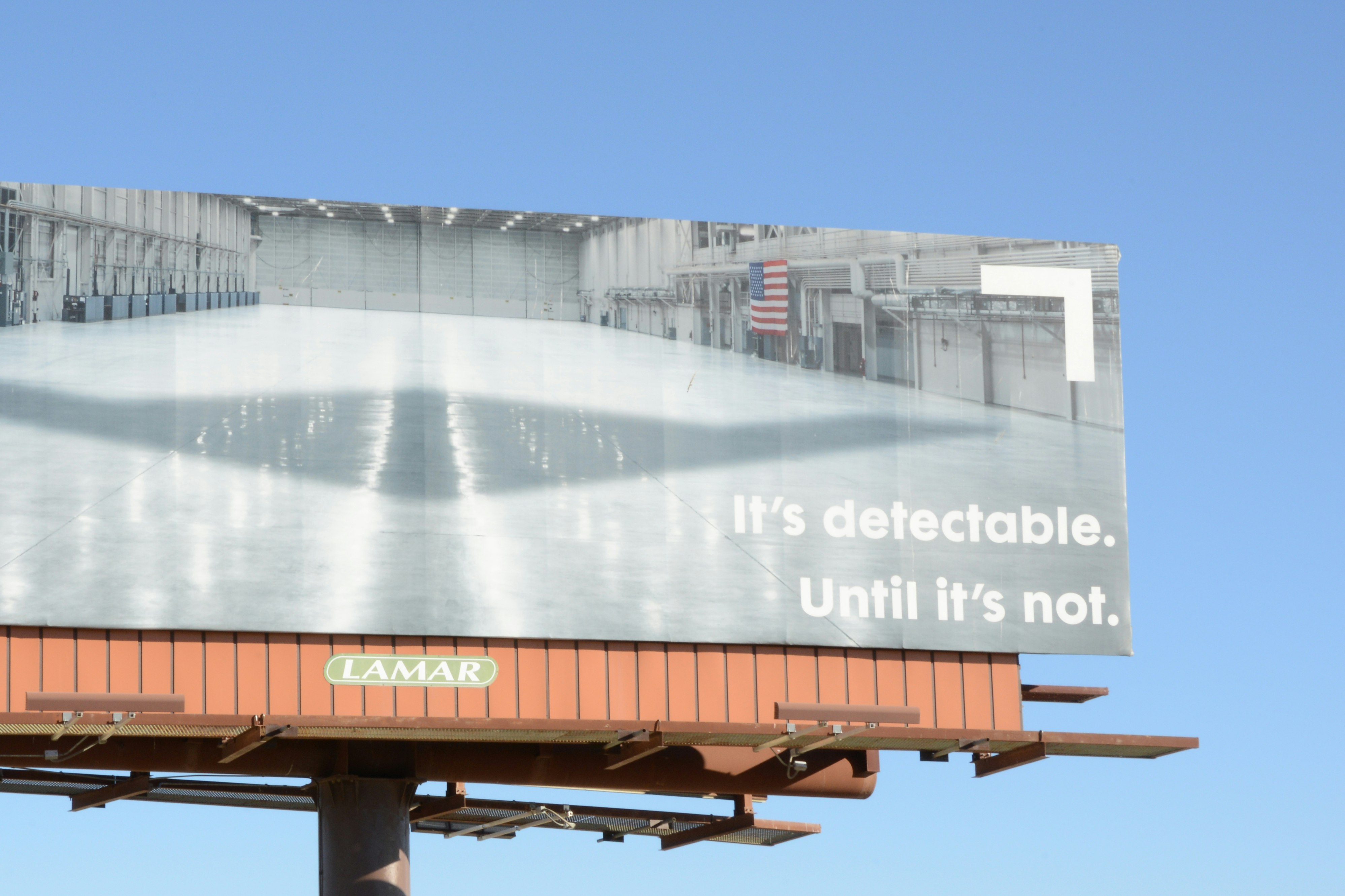 Billboard showing hangar interior with shadow of stealth aircraft cast on the floor. Text: “It’s detectable. Until it’s not.”