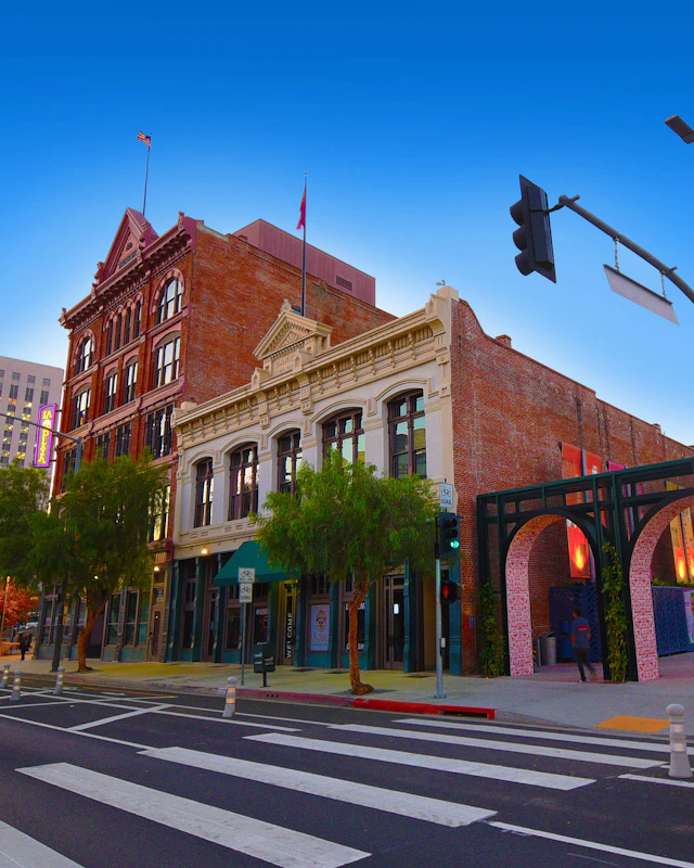 Exterior view of a two-story commercial building, with a brick facade and a cast-iron column storefront, next to a three-arch entryway.