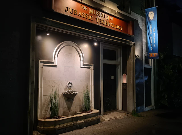 A photograph of the front of a building at night with lights shining on the wall.