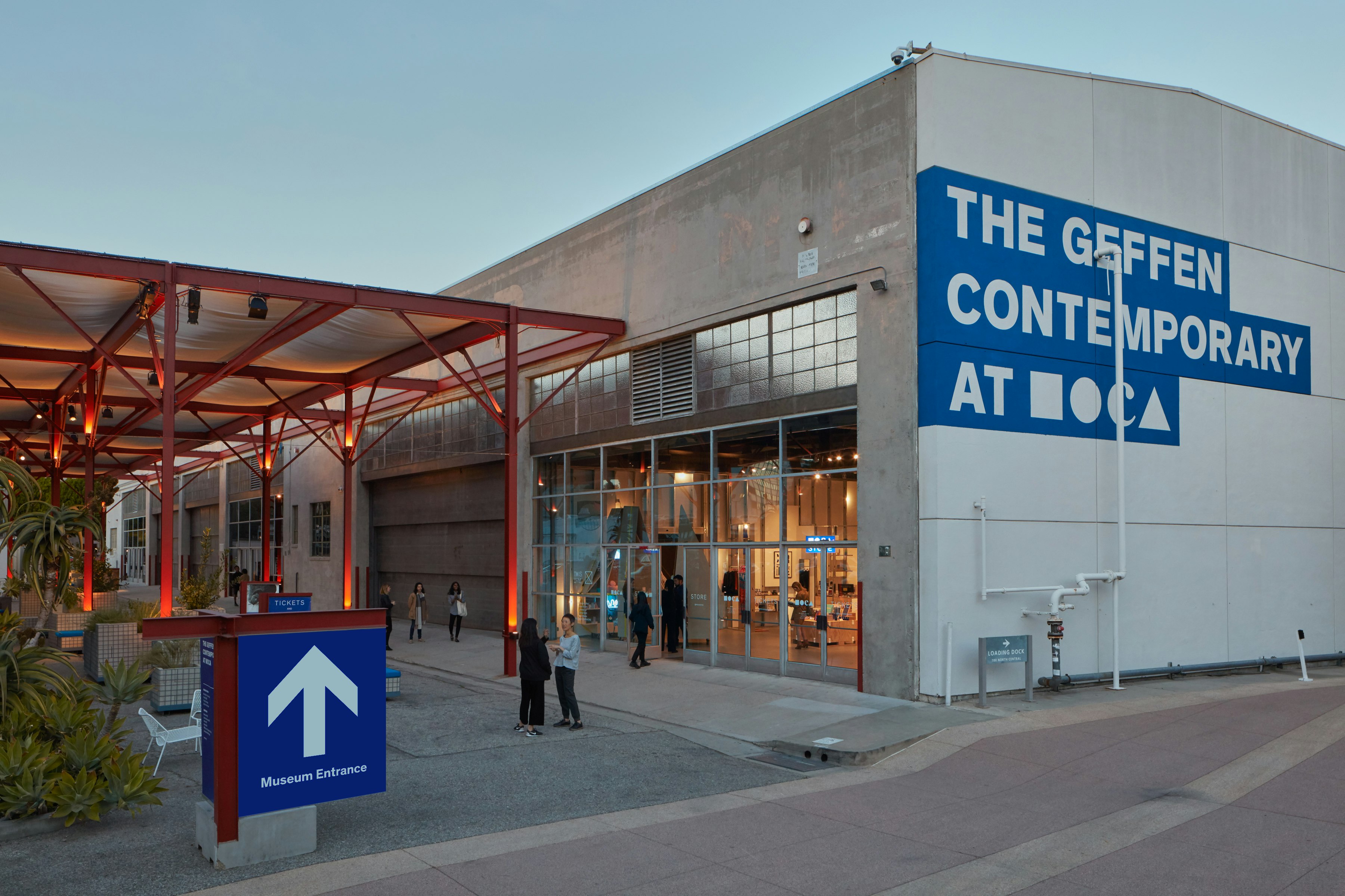 A photograph of a grey concrete building with an orange awning.